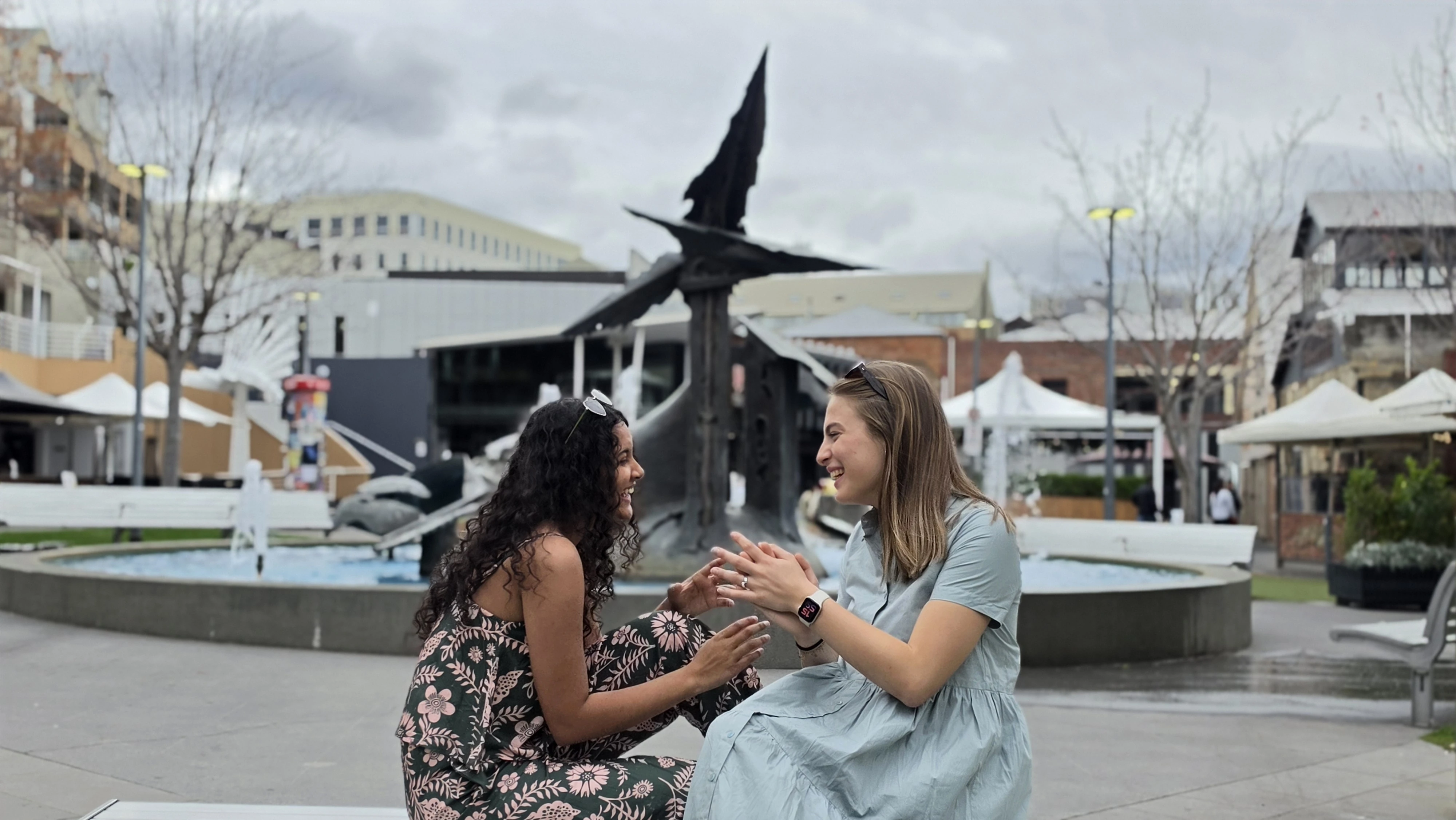 Two friends laughing in BINDY sage and floral pieces in the city